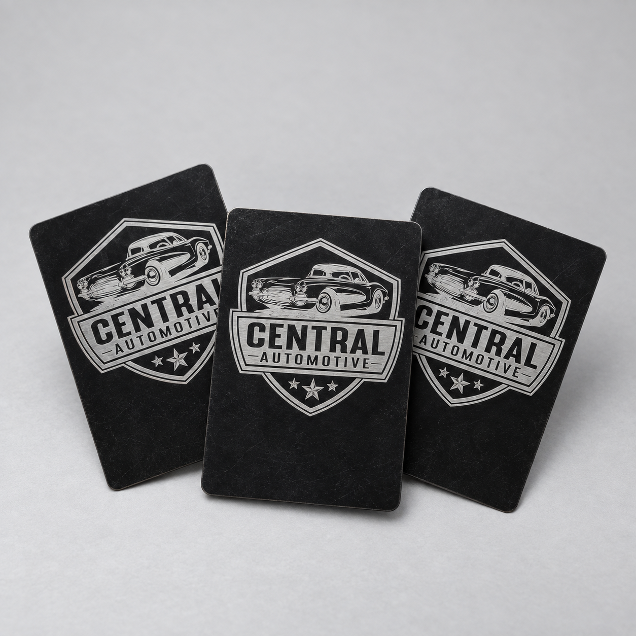 Three black metal cards engraved with the Central Automotive vintage car logo
