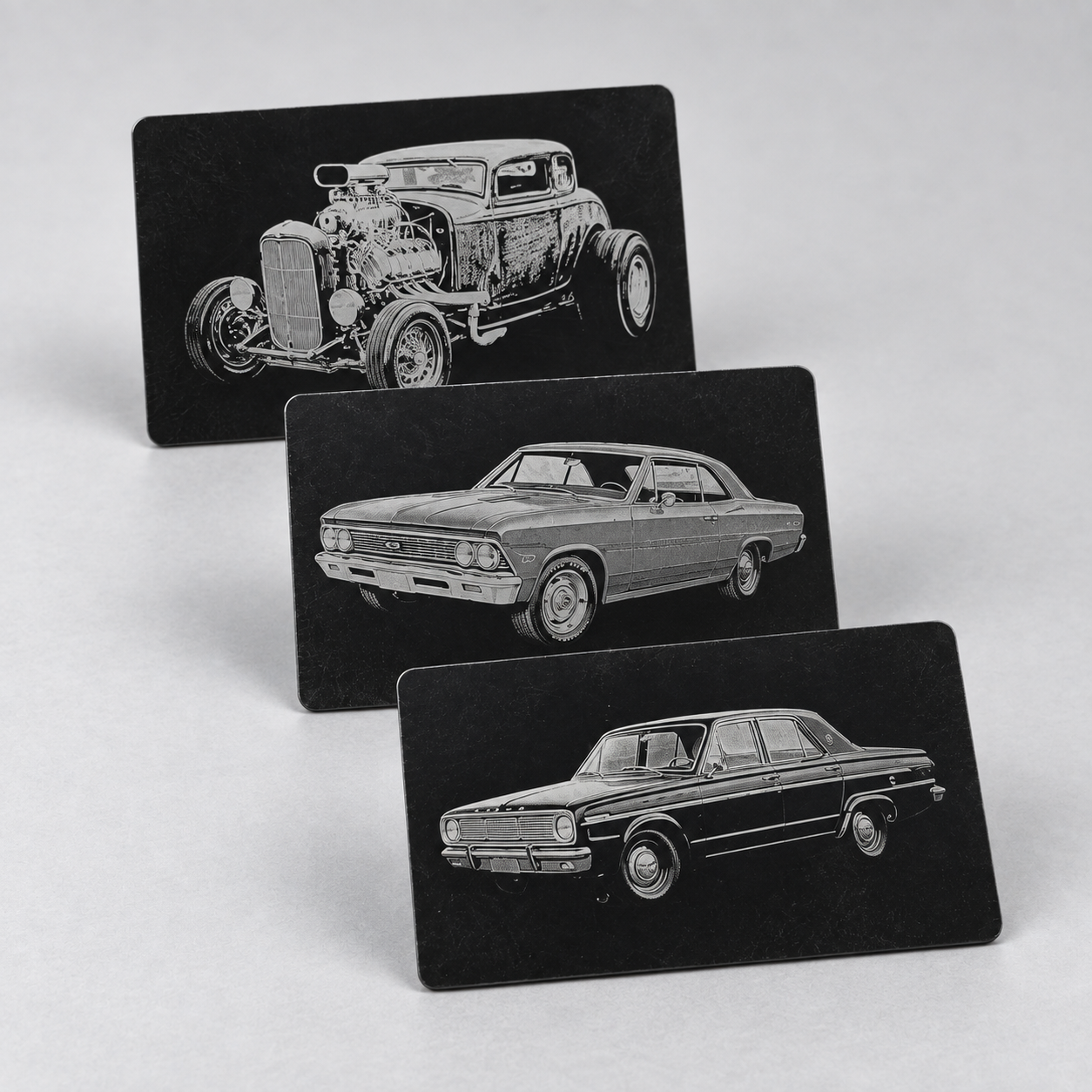 Three black metal cards engraved with a hot rod and two classic cars