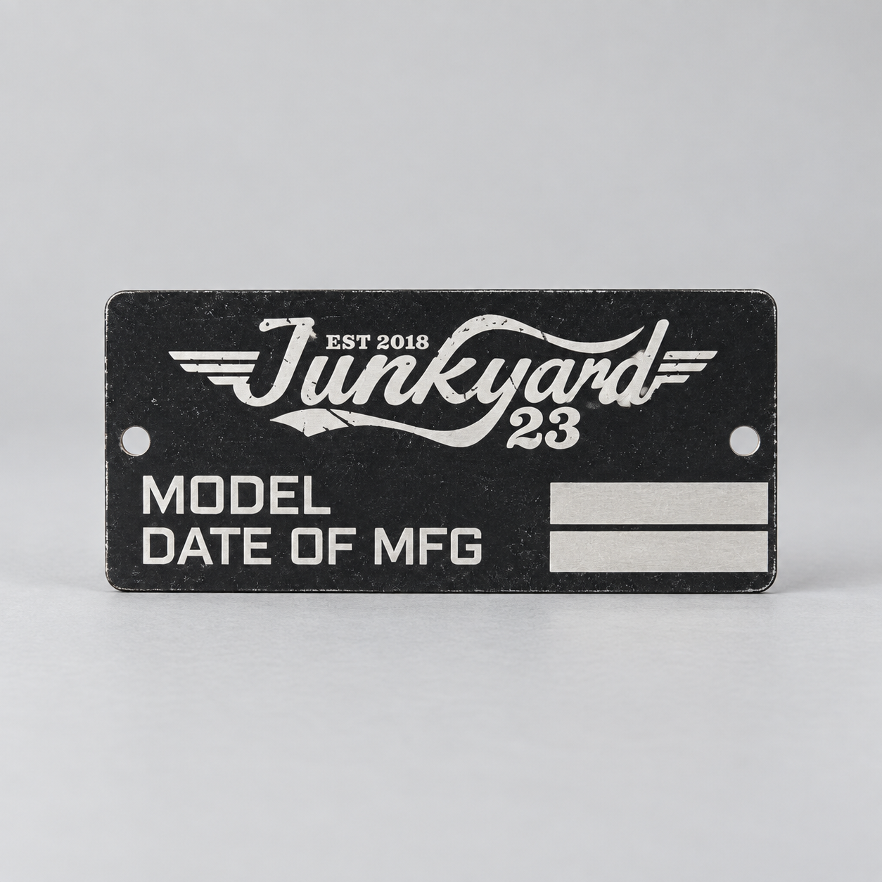 Black metal tag engraved Junkyard 23 with model and manufacturing date fields